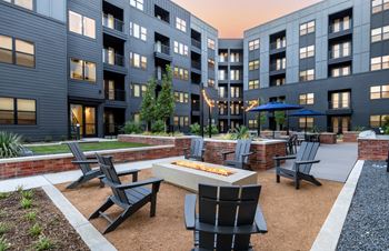 A modern outdoor seating area with black chairs and tables is set up in front of a building.